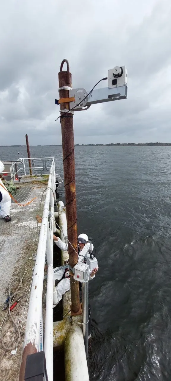 An mFL-12 lidar and an mHR-2 radiometer mounted on a mast standing above open water at Parentis, under an overcast sky