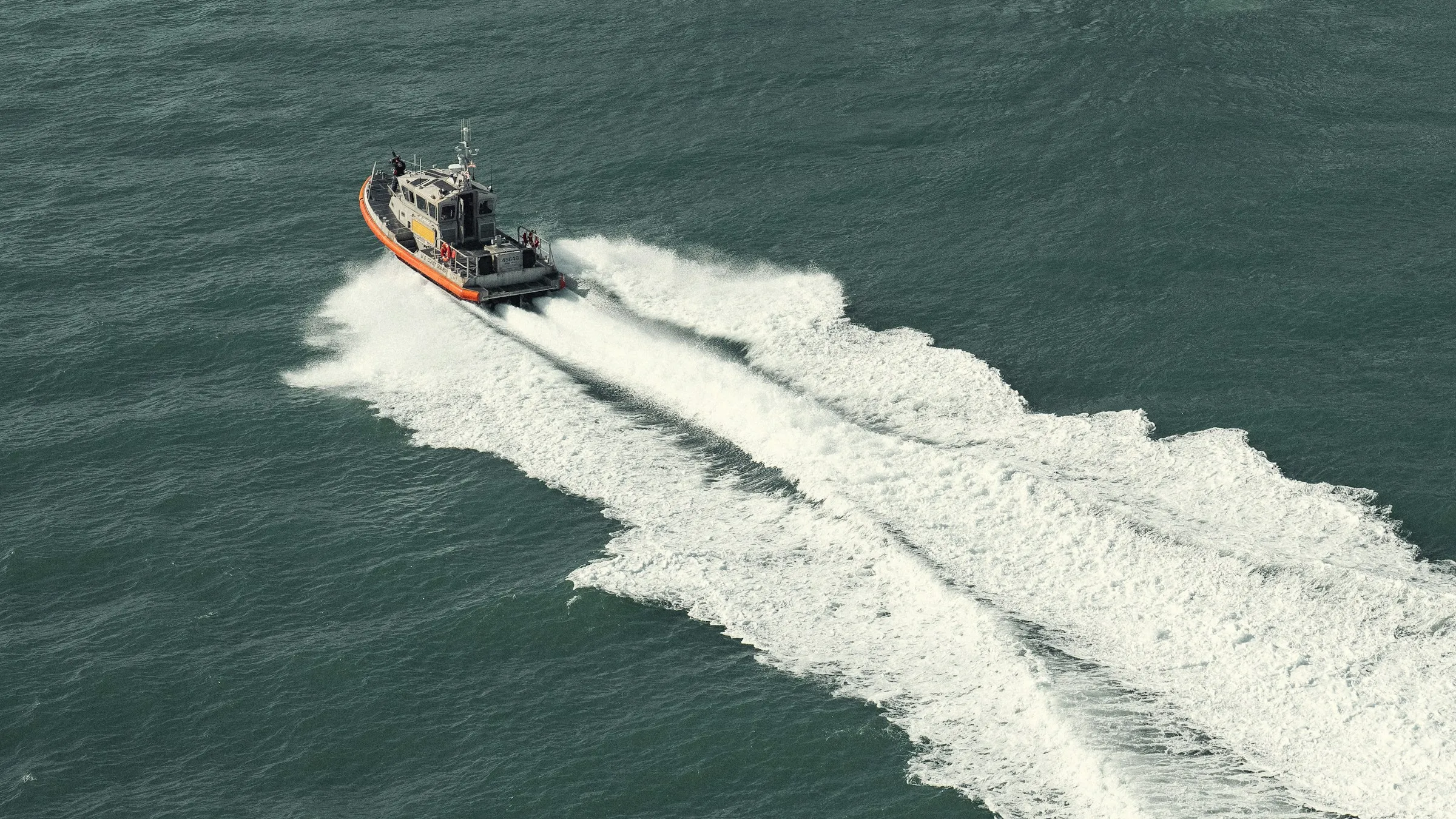 A survey vessel under way on open water, its wake drawn across the surface behind it
